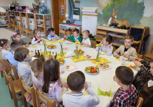 dzieci siedzą przy stole podczas poczęstunku