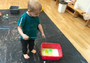 Chłopiec wkrapla kolorową wodę do cieczy