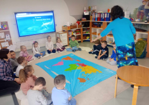 dzieci siedzą wokół mapy swiata