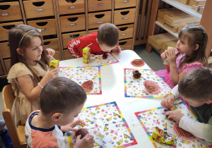 dzieci siedzą przy stole jedzą babeczki