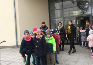 Dzieci stoja przed budynkiem 