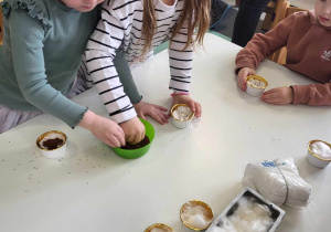 przedszkolaki wsypują ziarenka rzeżuchy do pojemniczków