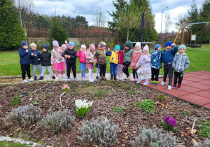 przedszkolaki podziwiają wiosenne kwiaty w ogrodzie