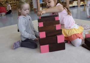 dziewczynki układają różową wieżę i brązowe schody
