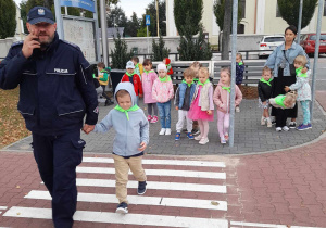 Pan policjant z chłopcem przechodzi przez pasy