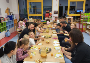 rodzice, dzieci panie siedzą przy stole degustując przekąski