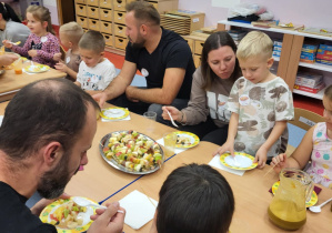 rodzice i dzieci siedzą przy stole degustując przekąski