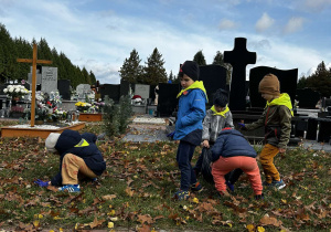 Dzieci porządkują teren cmentarza