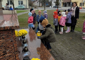 przedszkolaki stawiają zapalone znicze