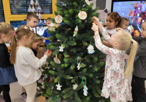 dzieci zawieszają ozdoby choinkowe