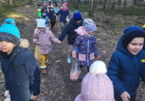 przedszkolaki idą w lesie do paśnika