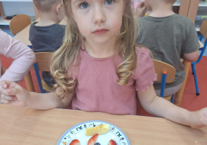 Dziewczynka układa na swoim talerzu owoce