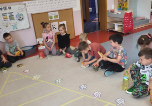 Dzieci siedzą w kole z produktami eko