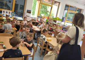 Dzieci siedzą przy stolikach z produktami ekologicznymi