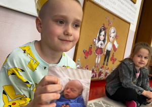 Chłopiec pokazuje zdjęcie z dzieciństwa