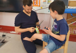fizjoterapeuta przykleja plaster chłopcu