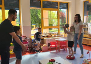 dzieci rzucają do siebie piłkę stojąc na balansujących poduszkach sensorycznych