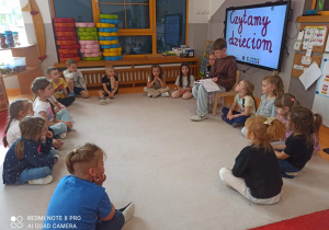 dzieci słuchają opowiadania czytanego przez Jasia