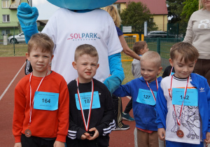 chłopcy pozują z medalami i maskotką