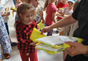 Pani Ewa rozdaje dzieciom kamizelki odblaskowe od FRGK