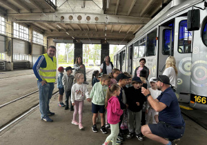Dzieci słuchają opowieści pana na zajezdni tramwajowej