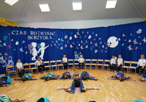 dziewczynki w strojach motyli siedzą na podłodze