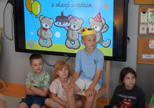 chłopiec w koronie na głowie siedzi na krześle