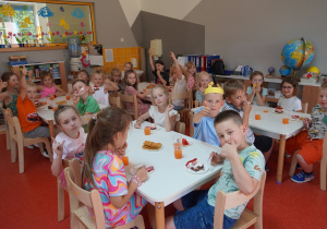 dzieci siedzą przy stolikach