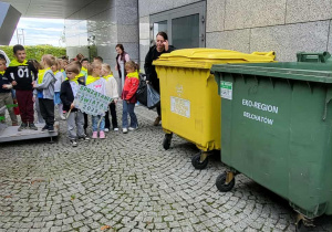 Dzieci wyrzucają śmieci do odpowiednich pojemników