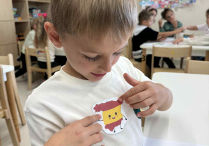 chłopiec nakleja naklejke z flaga Hiszpani na koszulkę