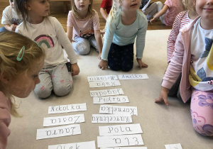 dzieci siedzą na dywanie z imionami