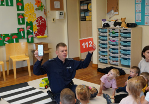 policjant pokazuje numer alarmowy