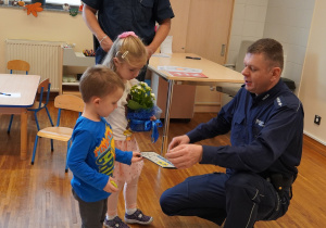 dzieci wręczają policjantom laurkę i kwiaty