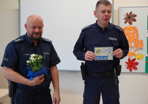 policjanci trzymają kwiaty i laurkę