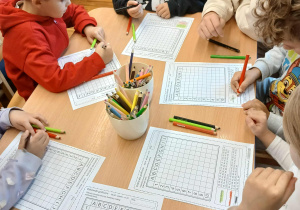 Dzieci wykonują kartę pracy z kodowaniem