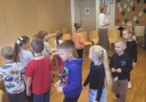dzięci wraz z nauczycielką angielskiego chodzą w kole i śpiewają piosenke po angielsku