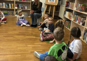 dzieci siedzą na dywanikach w bibliotece