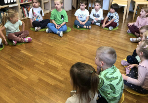 dzieci siedzą na dywanikach w bibliotece