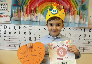 Chłopiec pozuje z dyplomem i sercem