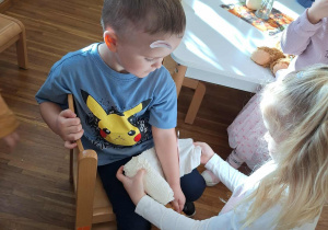 dziewczynka bandażuje rękę chłopcy