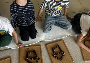 Dzieci układają domek z darów jesieni