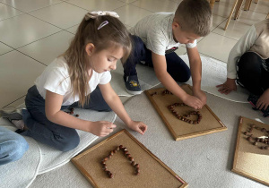 Dzieci układają domek z darów jesieni