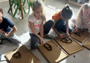 Dzieci układają domek z darów jesieni