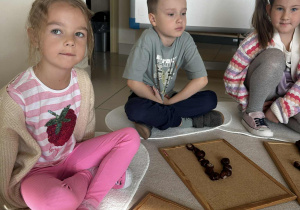 Dzieci układają cyfrę 1 z kasztanów