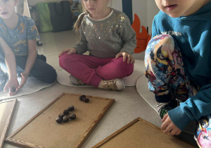 Dzieci układają cyfrę 1 z kasztanów