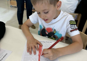 chłopiec maluje czerwoną kredką