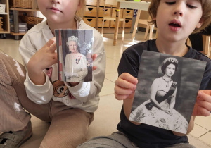 dziewczynka i chłopiec trzymają zdjęcia królowej Elżbiety II