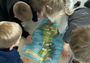 dzieci w kręgu ogladają mape Wielkiej Brytanii