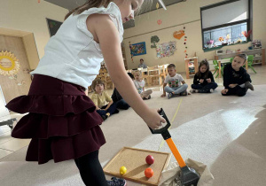 dziewczynka trzyma chwytak i wyciąga z worka owoc