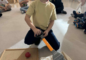 chłopiec trzyma chwytak i wyciąha z worka owoc